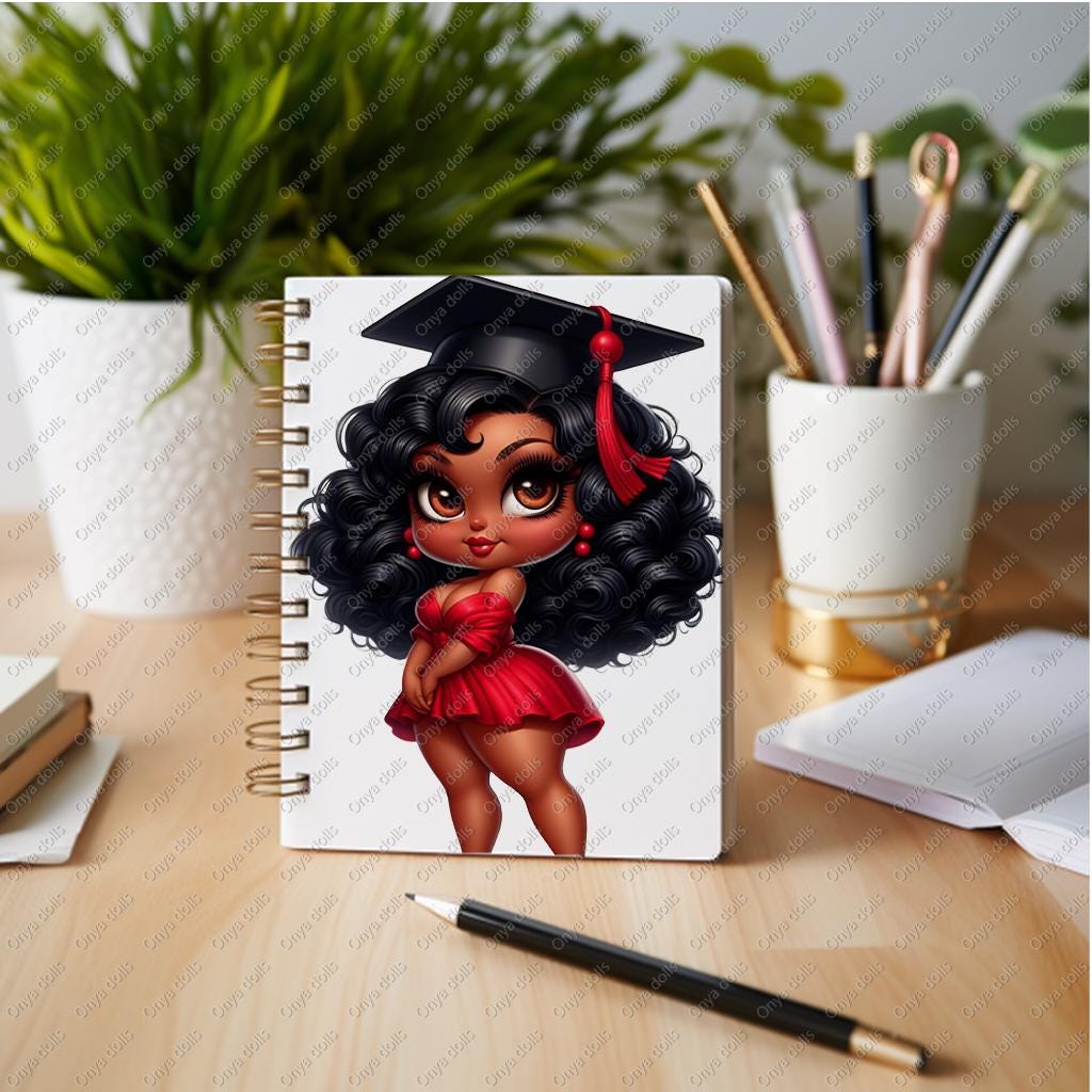 Notebook with a graduation-themed cover featuring a girl in a red dress and cap on a desk with stationery items.