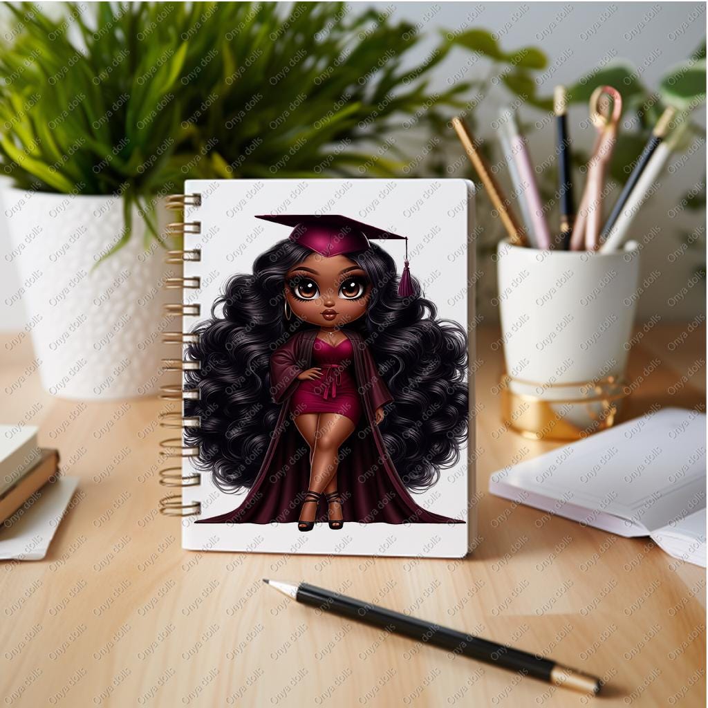 Notebook with a graduation-themed cover featuring an illustrated character on a desk with stationery items.